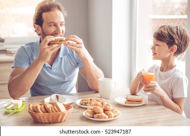 Father and son are talking and smiling while having a breakfast in kitchen