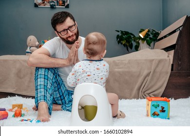 Father And Son. Father Teaches A Child To Walk On A Potty. Father Makes An Appealing Gesture With His Hands. Dad Is Tired Of Waiting. The Child Is Playing. Baby Toiletries. Potty Training.baby