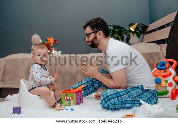 Father and son. Father teaches a child to walk\
on a potty. Father does begs and asks. The child is playing. Baby\
toiletries. Potty\
training.