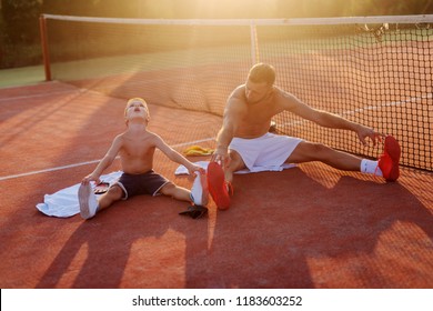 Father and son training together. Sitting on training field and stretching after hard raining. Having fun together. - Powered by Shutterstock