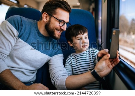Father and son travel together by fast train and taking selfie photo.