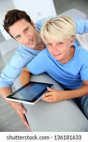 Father and son using digital tablet at home