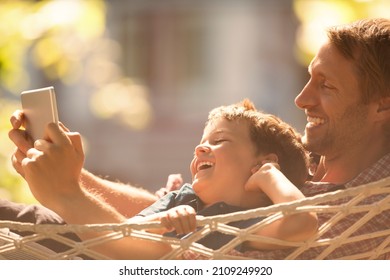 Father and son using digital tablet in hammock - Powered by Shutterstock