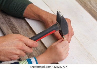 Father And Son Using Hammer And Nail Spike. Boy Helping His Dad With Building Work At Home. Family Concept