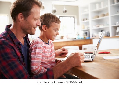 Father and son using laptop computer at home