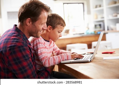 Father and son using laptop computer at home