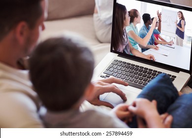 Father and son using laptop in house against casual business people in office at presentation