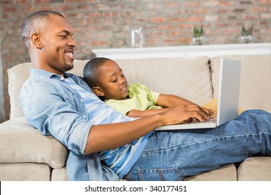Father and son using laptop on the couch in living room