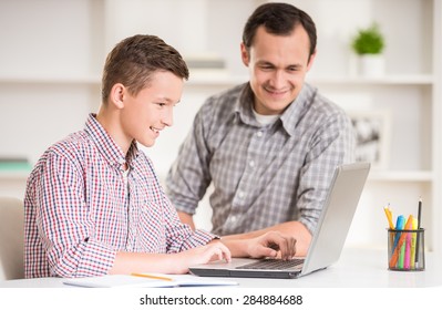 Father and son using laptop together at home.
