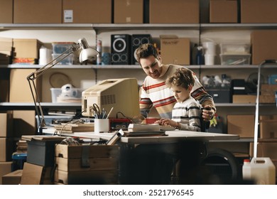 Father and son using an old PC in the garage, he is teaching him how to use a computer
