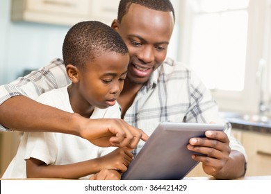 Father and son using tablet together in the kitchen