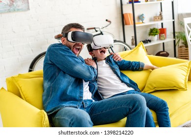 father and son in vr headsets yelling while experiencing Virtual reality on couch at home - Powered by Shutterstock