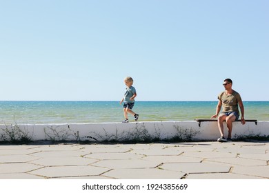 Father and son walking and playing on the Black Sea embankment in Crimea. Summertime, vacaion, family concept.