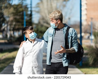 Father And Son Walking To School Wearing Face Mask And A White Smock (an Argentinian White Coat For Public Schools). Virus Spread Concept