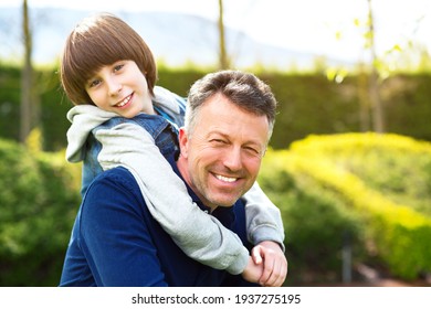 Vater mit Sohn, der im Frühlingspark spaziert. Schöner reifer Mann und süßer 11-jähriger Junge posieren im Frühling draußen.