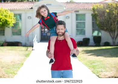 Father and son walking trough school park. Father giving son piggyback ride after come back from school.