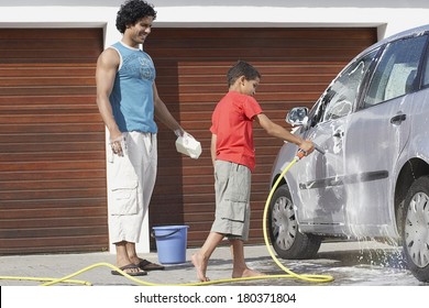 Father And Son Washing The Car At Home Garage