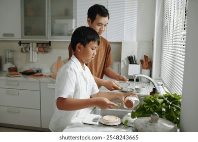 Father and Son Washing Dishes Together in the Kitchen - Powered by Shutterstock