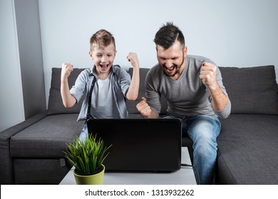 Father and son watching football in a laptop at home. Emotional man and boy, cheering favorite team. The concept of family enthusiasm, emotions, family time, copy space.