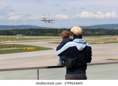 Father And Son Watching A Plane During Take Off