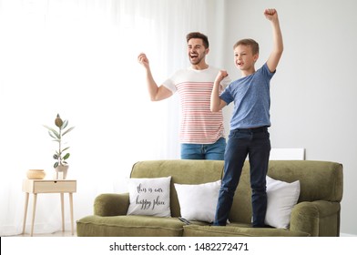 Father With Son Watching Sports On TV At Home