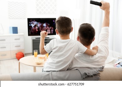 Father and son watching television at home. Leisure and entertainment concept