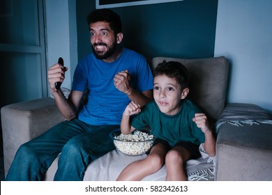 Father And Son Watching TV And Cheering At Night