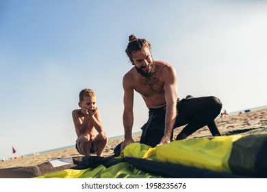 Father and son in wetsuits with kite equipment for surfing - Powered by Shutterstock