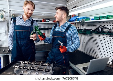 Father and son work at the auto service. Two mechanics work with the details of the car. Two mechanics drink beer during a working break. - Powered by Shutterstock