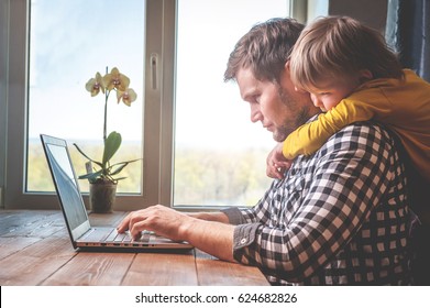 Father and son working on laptop. businessman working from home and watching child. spending time with kid. Young man working on computer. StartUp. Freelance concept. successful modern family. 