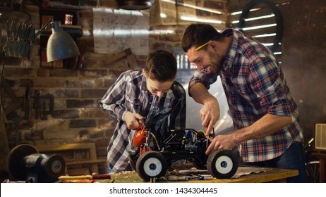 Father And Son Are Working On A Radio Control Toy Car In A Garage At Home.