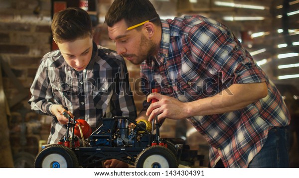 Father and son are working on a radio control toy\
car in a garage at home.
