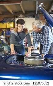 Father And Son Working Together On A Classic Car In A Garage