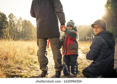 father with sons walking in autumn time at sunset