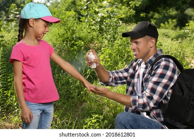 Father Spraying Tick Repellent On His Little Daughter's Arm During Hike In Nature