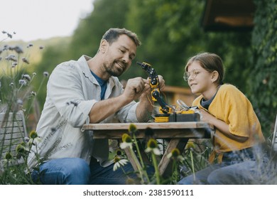 Father supporting daughter in pursuing robotics, science, IT technologies and programming. Young girl assembling a simple robot and her dad helping her. - Powered by Shutterstock