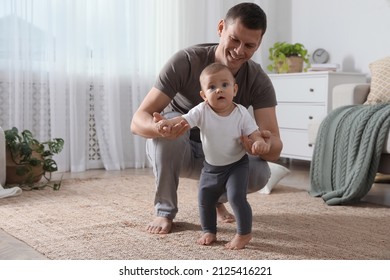 Father supporting his baby daughter while she learning to walk at home