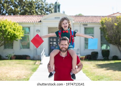 Father supports and motivates son. Kid going to primary school. First day of fall. Dad and son having fun near school yard. Concept of friendly family.