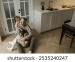 A father is surrounded by the love of his two daughters. The older daughter gives him a kiss on the cheek while the younger one hides her face in his shoulder. 