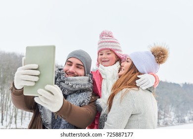 Father Takes Happy Family Selfie With Tablet In Winter