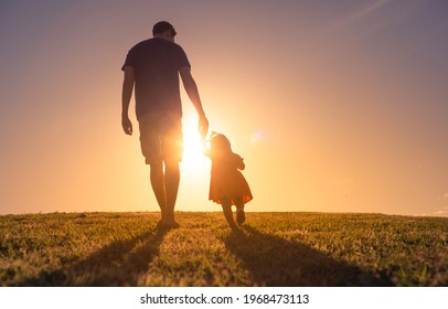 Father Taking Care Of His Daughter. Dad Child Walking Together In The Sunset Outdoors Holding Hands. Childhood, Parenting And Fathers Day Concept. 