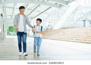 Father taking his son going to school, a man holding child hand while walking to school together.