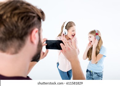 father taking photo of mother and daughter listening music with headphones and singing isolated on white - Shutterstock ID 611581829
