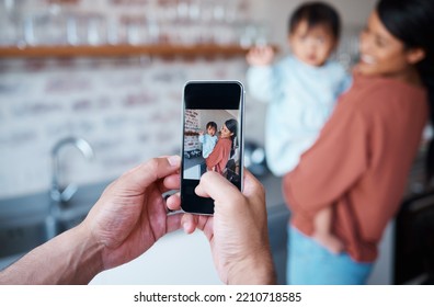 Father Taking A Picture Of Mother And Baby On A Phone In The Kitchen Of Their Family House. Love, Care And Man Taking Photo On Smartphone Of A Happy And Proud Mom Bonding With Her Child In Their Home