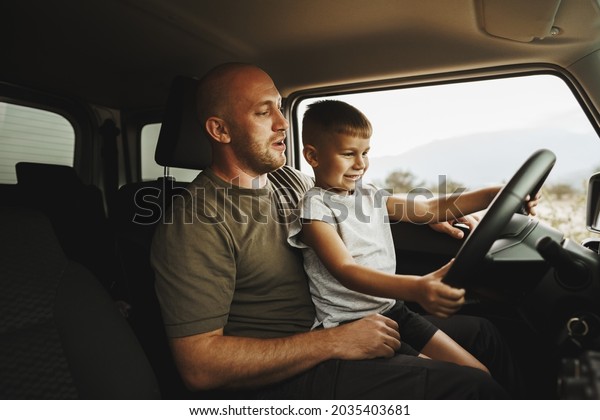 Father teaches
little son to drive on road
trip