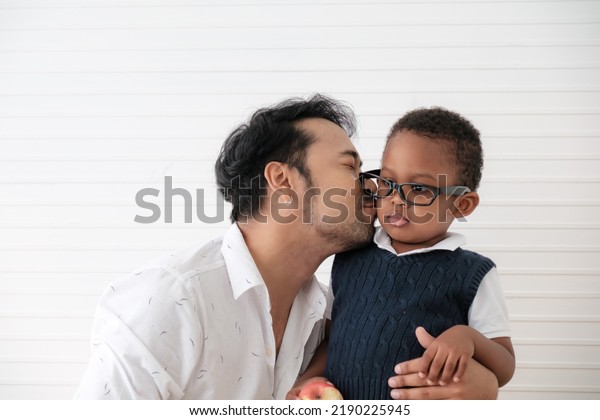 Father teaches son to eat apples and is glad that\
son eats apples