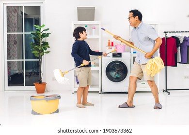 Father Teaching Asian Kid Little Boy Son Having Fun Doing Household Chores Cleaning And Washing Floor Wiping Dust With Mopping And Vacuum Cleaner While Cleaning House Together At Home