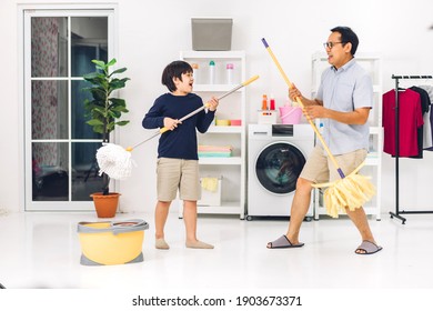 Father Teaching Asian Kid Little Boy Son Having Fun Doing Household Chores Cleaning And Washing Floor Wiping Dust With Mopping And Vacuum Cleaner While Cleaning House Together At Home