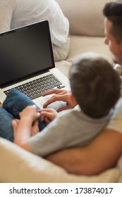 Father teaching boy in using laptop at home