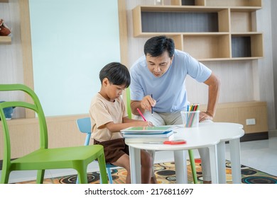 Father Teaching Children Homework In Living Room.